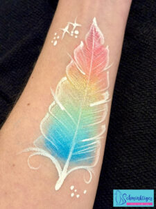 Feder in Regenbogenfarben geschminkt auf Arm