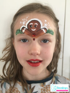 Kind mit weihnachtlichem Lebkuchenmann auf Stirn geschminkt